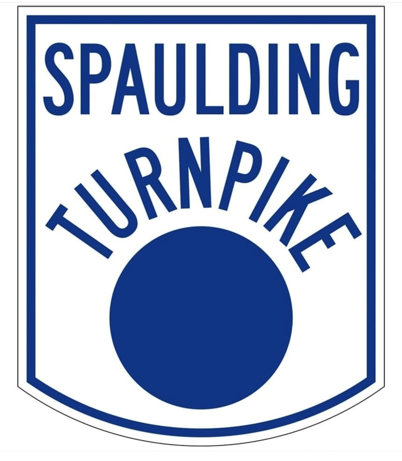This is the sign for the Spaulding Turnpike. There is a blue border on this sign, which is square at the top and curved at the bottom. It is longer than it is wide. The words Spaulding Turnpike appear at the top of the sign. The word Spaulding is level, and the word Turnpike is arched over a large blue circle. New Hampshire personal injury law firm Attorney Buckley features this sign.
